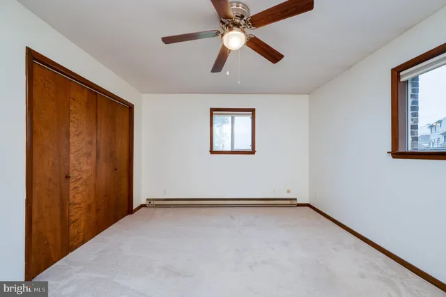 an empty room with windows and fan