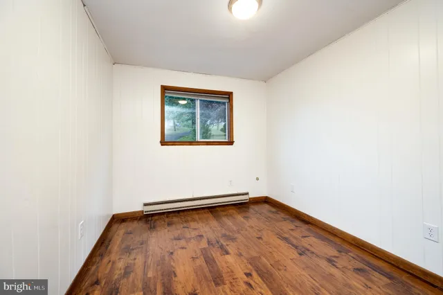 an empty room with wooden floor and window