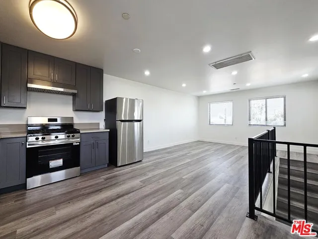 a kitchen with stainless steel appliances granite countertop a refrigerator stove and wooden floor