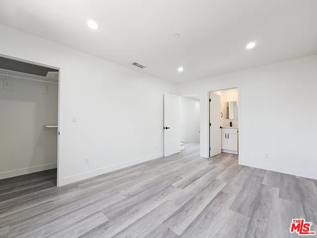 a view of an empty room with wooden floor and closet