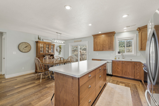 18573 South Marsh Valley Road Downey, ID 83234 - Photo 8 of 32 Kitchen featuring wood finish cabinetry, a center island, stainless steel appliances, light countertops, and a textured ceiling