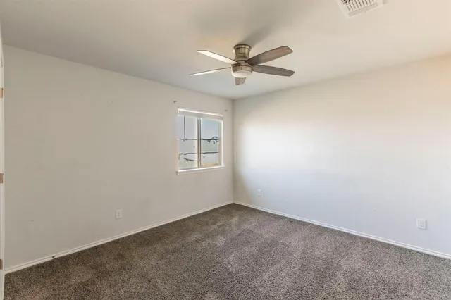 an empty room with a ceiling fan and wooden floor
