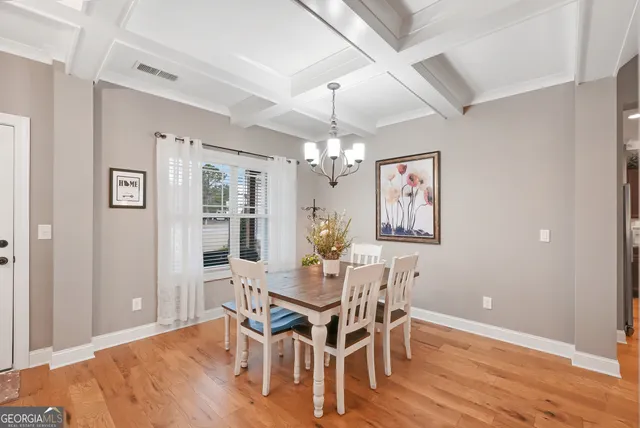a dining room with wooden floor a chandelier a wooden table and chairs