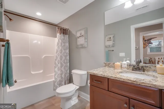a bathroom with a granite countertop sink toilet and shower