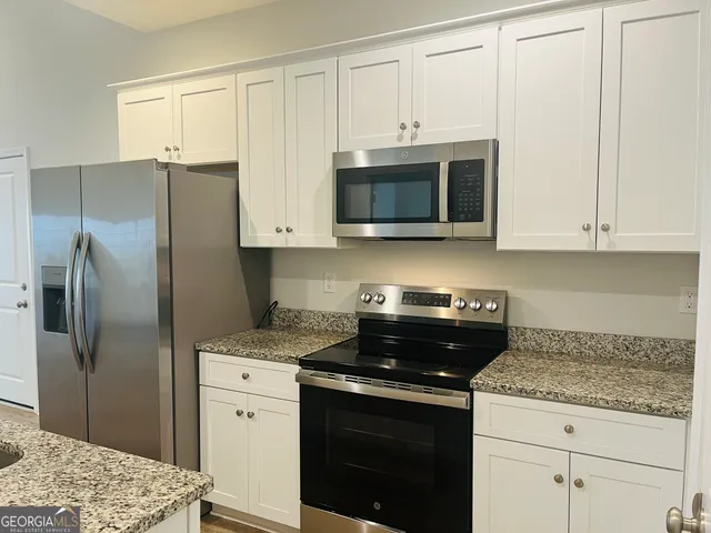 a kitchen with granite countertop white cabinets and stainless steel appliances