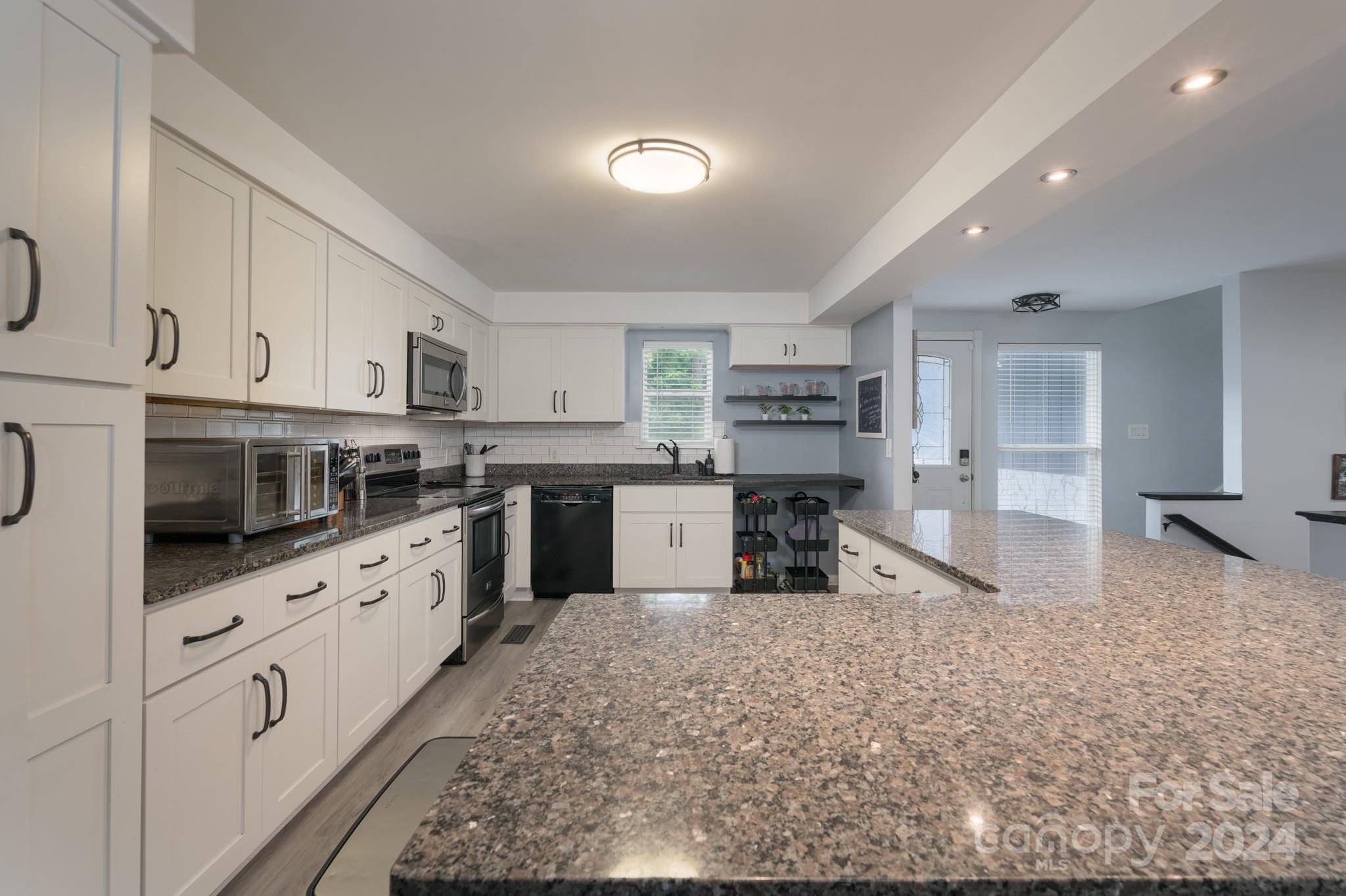 4093 Marquesas Avenue Tega Cay, SC 29708 - Photo 3 of 38 a kitchen with stainless steel appliances granite countertop a stove top oven a sink a refrigerator and white cabinets