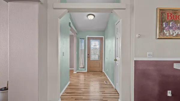 a view of a hallway with wooden floor and a bathroom