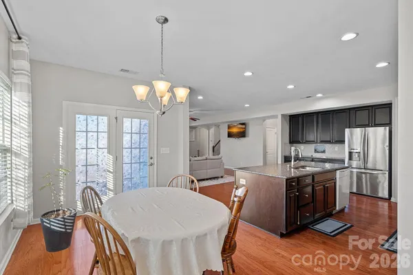 a kitchen with stainless steel appliances granite countertop a stove a sink a refrigerator a dining table and chairs