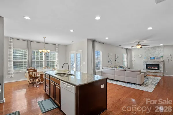 a living room with stainless steel appliances granite countertop furniture a fireplace and a view of kitchen