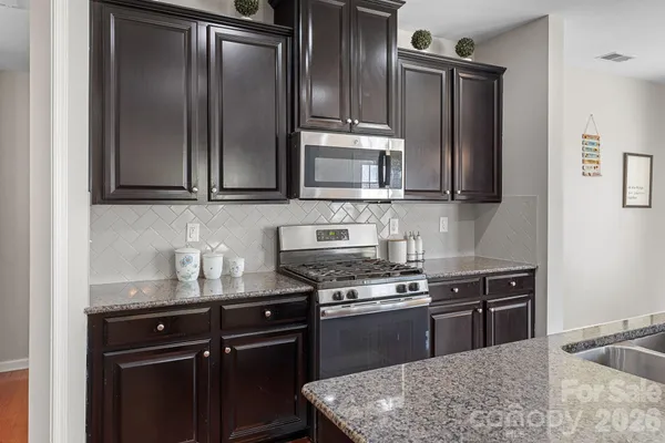 a kitchen with granite countertop a refrigerator stove and microwave