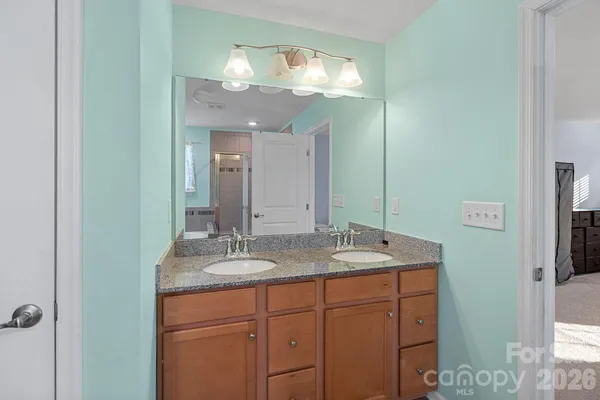 a bathroom with a granite countertop sink a large mirror and a shower