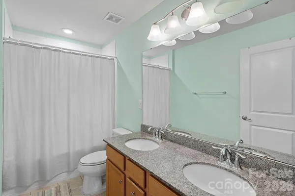 a bathroom with a granite countertop double vanity sink and a mirror