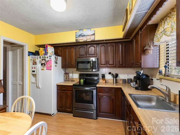 a kitchen with stainless steel appliances granite countertop a sink stove refrigerator granite counter tops wooden cabinets a dining table and chairs