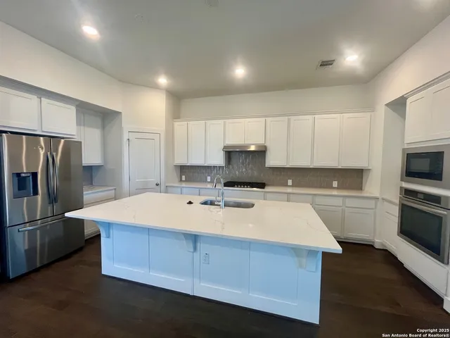 a kitchen with granite countertop white cabinets and appliances