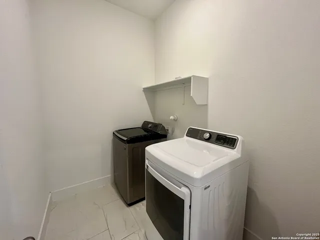 an empty room with wooden floor chandelier and windows
