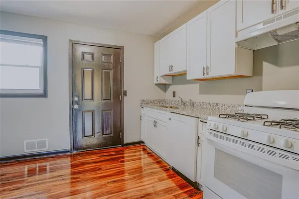 a kitchen with granite countertop white cabinets and white appliances