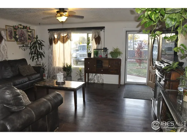 a living room with furniture large window and wooden floor