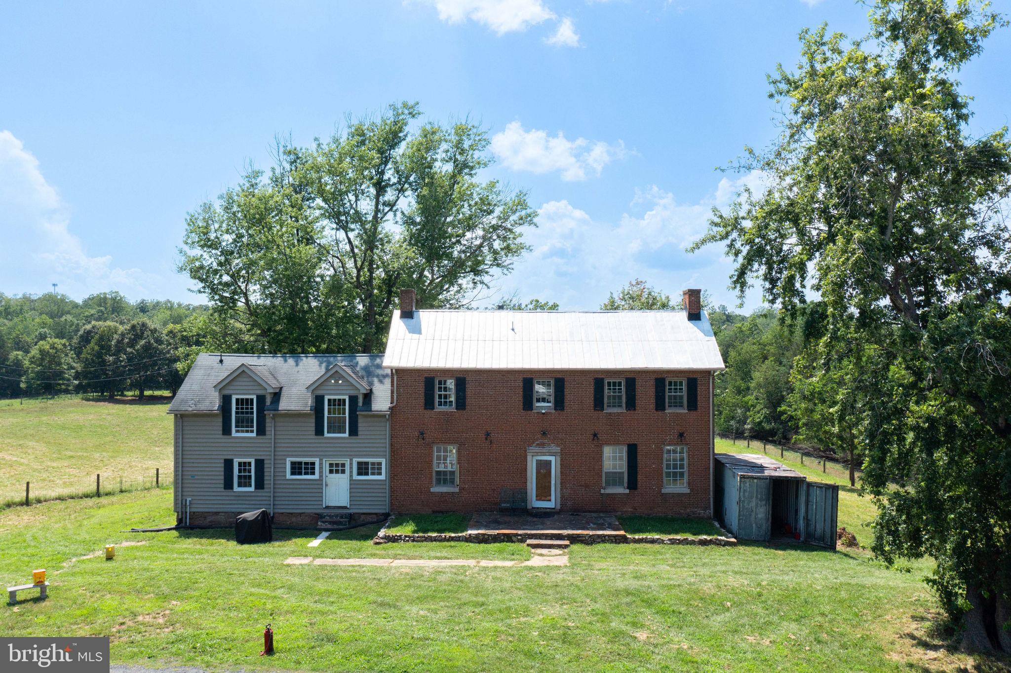 a view of a house with a big yard plants and large trees