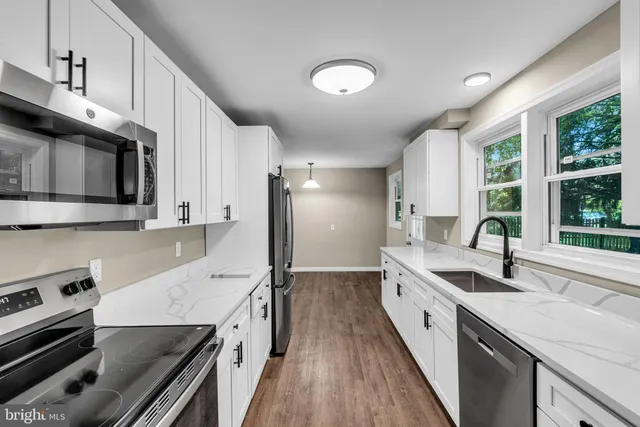 a kitchen with stainless steel appliances a sink dishwasher a stove a microwave oven and a refrigerator with wooden floor