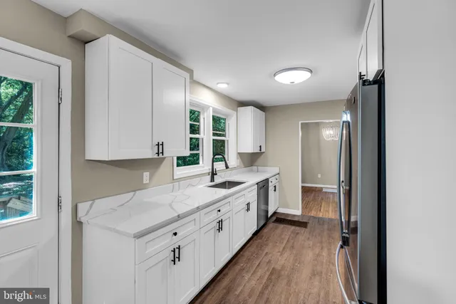 an empty room with wooden floor cabinet and windows