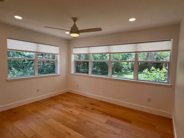 a view of empty room with wooden floor and fan