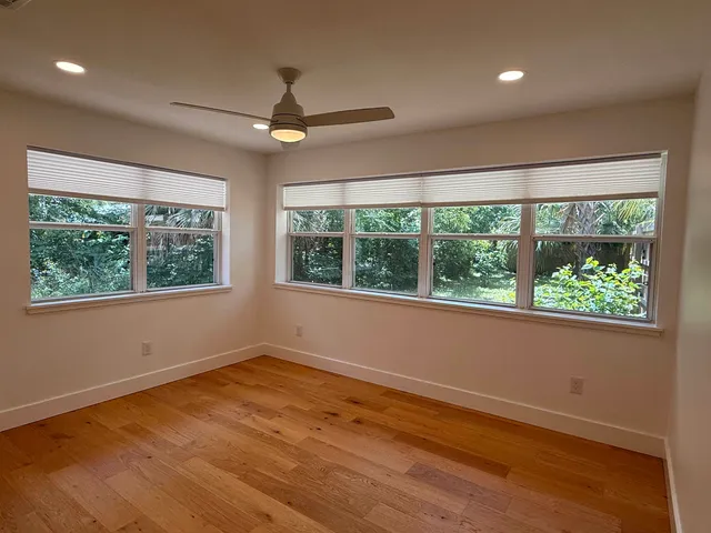 a view of empty room with wooden floor and fan