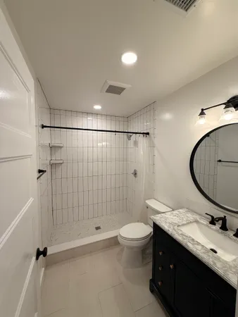 a bathroom with a double vanity sink toilet mirror and shower