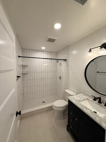a bathroom with a double vanity sink toilet mirror and shower