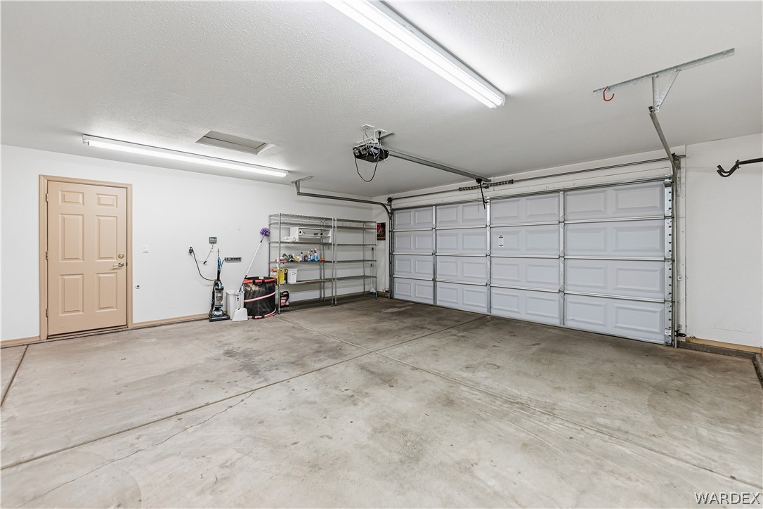3973 Prairie View Drive Kingman, AZ 86409 - Photo 32 of 34 The property features an attached garage with a concrete floor, bright overhead lighting, and a white paneled garage door