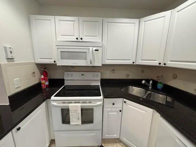 a kitchen with white cabinets and white appliances