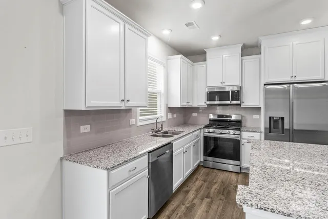 a kitchen with stainless steel appliances granite countertop a stove a sink and a refrigerator