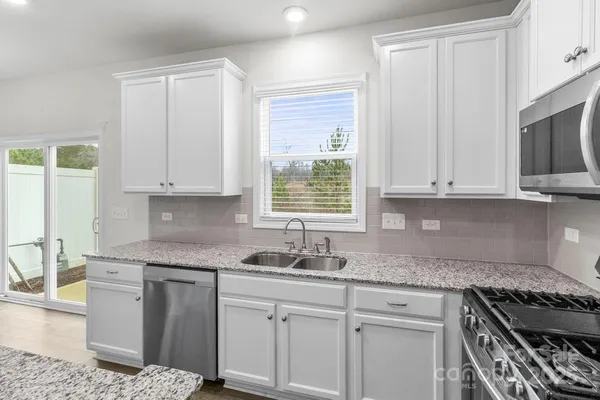 a kitchen with granite countertop white cabinets and a stove