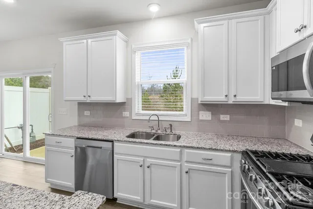 a kitchen with granite countertop white cabinets and a stove