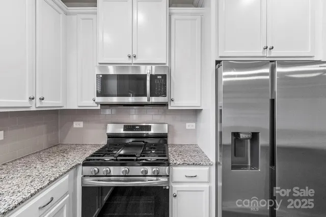 a kitchen with stainless steel appliances granite countertop a stove a refrigerator and a microwave