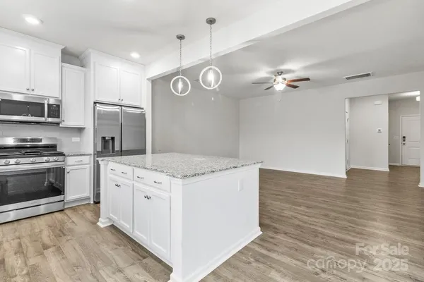 a kitchen with stainless steel appliances granite countertop a stove a refrigerator and a microwave oven