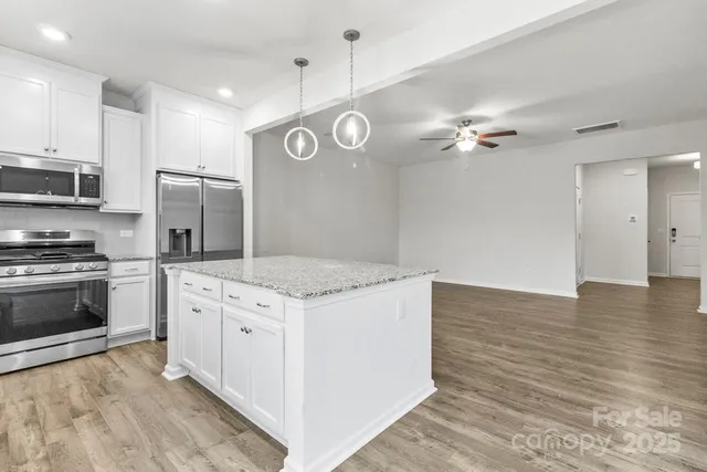 a kitchen with stainless steel appliances granite countertop a stove a refrigerator and a microwave oven