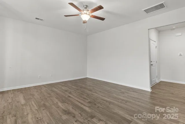 an empty room with wooden floor and fan