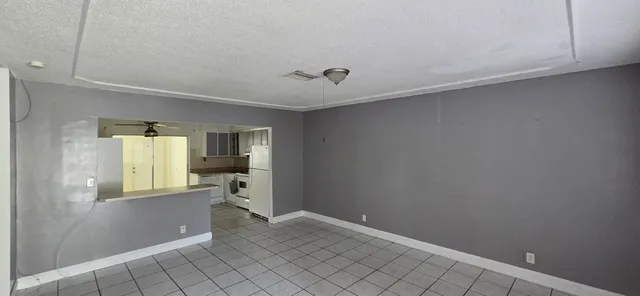 a view of a hallway to a room with wooden floor and windows
