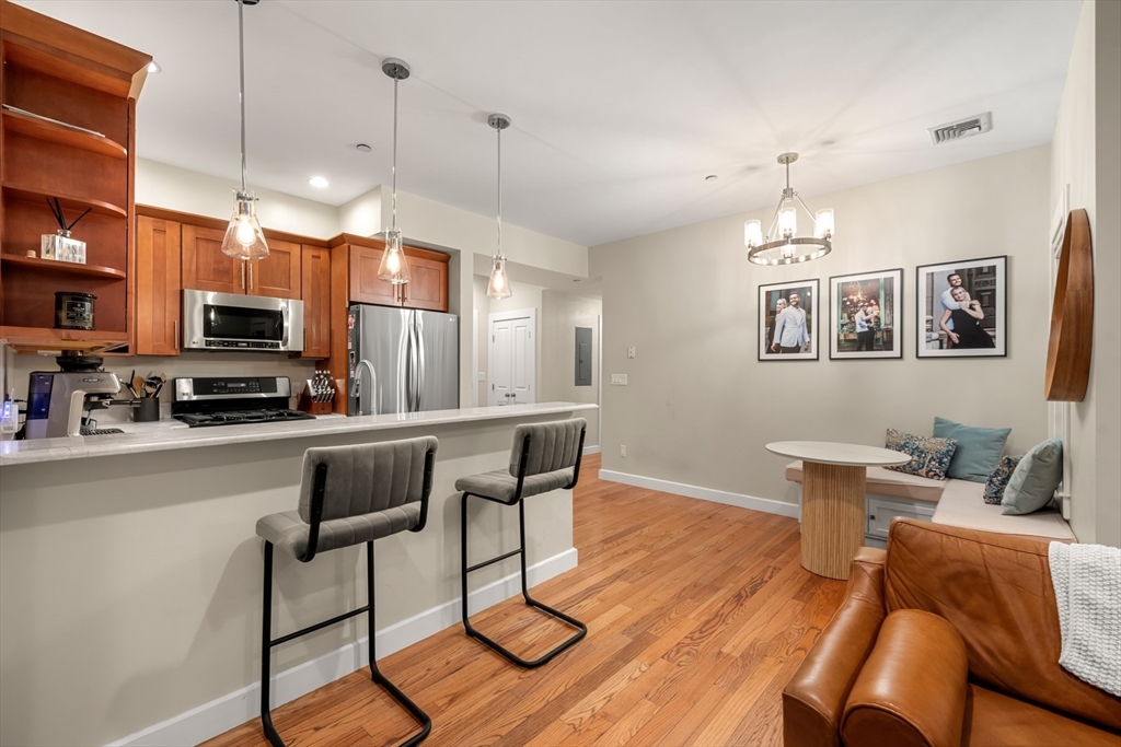 345 West Broadway, Unit 4 Boston, MA 02127 - Photo 8 of 26 a kitchen with stainless steel appliances a dining table chairs stove refrigerator and cabinets