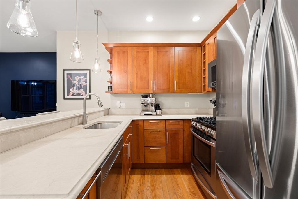 345 West Broadway, Unit 4 Boston, MA 02127 - Photo 9 of 26 a kitchen with stainless steel appliances granite countertop a refrigerator a sink dishwasher a stove and white countertops with wooden floor