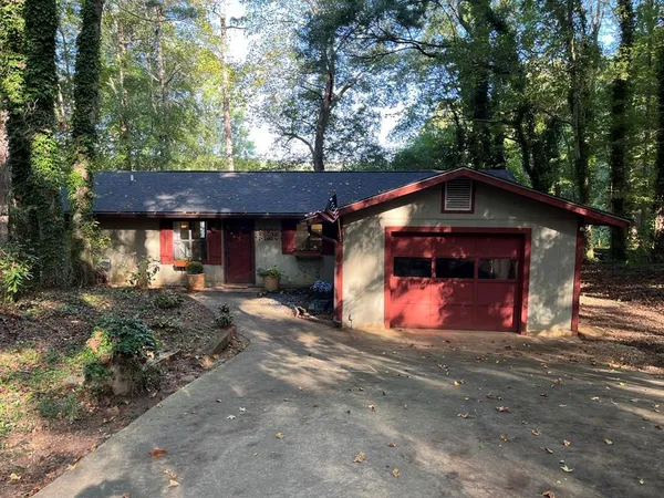 a view of a barn with wooden fence and large trees