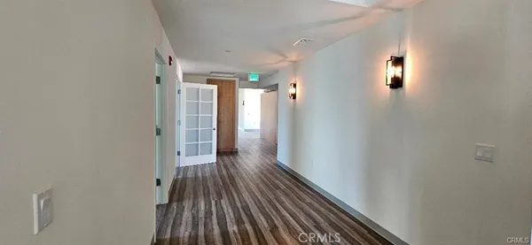 a view of a hallway with wooden floor and a bathroom