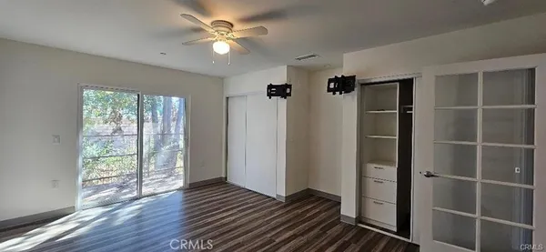 a view of a hallway with wooden floor and a ceiling fan