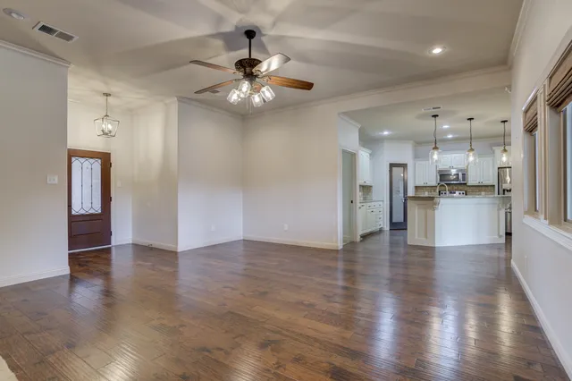 an empty room with wooden floor and kitchen view