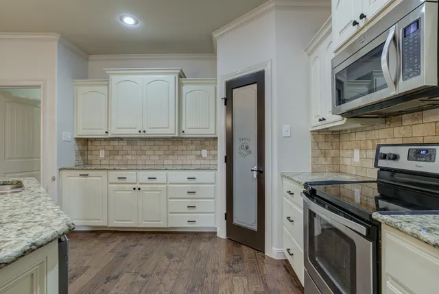 a kitchen with granite countertop cabinets stainless steel appliances and a wooden floor