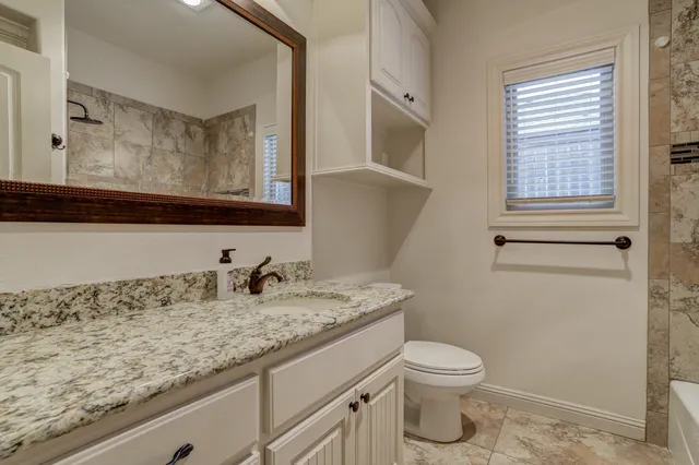 a bathroom with a granite countertop sink toilet and mirror
