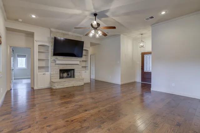 a view of a livingroom with a flat screen tv wooden floor and a ceiling fan