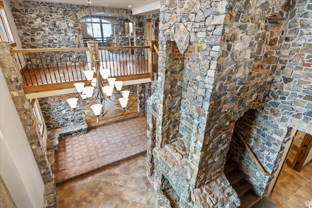 246 Woods Creek Road Morgan, UT 84050 - Photo 53 of 69 Stone-clad walls with archways, a grand chandelier, wood-finish flooring, and a stone-built fireplace