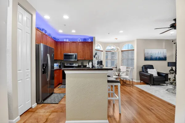 a kitchen with stainless steel appliances a refrigerator a stove a sink dishwasher and a dining table with wooden floor