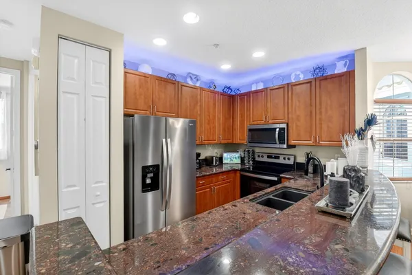 a kitchen with stainless steel appliances granite countertop a refrigerator a stove a sink a oven with a dining table and chairs